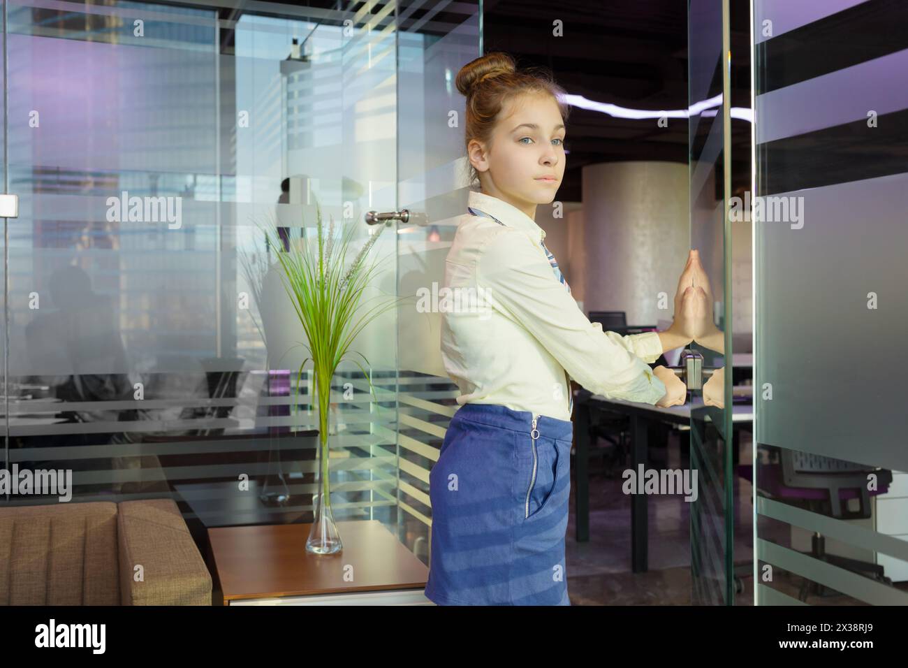 Una bella ragazza apre una porta di vetro in un ufficio moderno con pareti di vetro Foto Stock