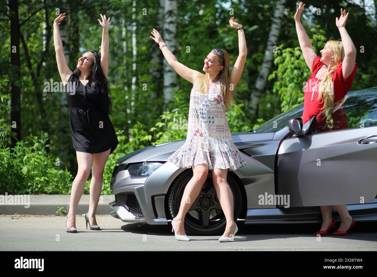 MOSCA - 19 giu 2016: Tre belle ragazze felici (con rilasci di modelli) con capelli lunghi allegramente ridendo e ingannando vicino all'auto sportiva di fronte Foto Stock