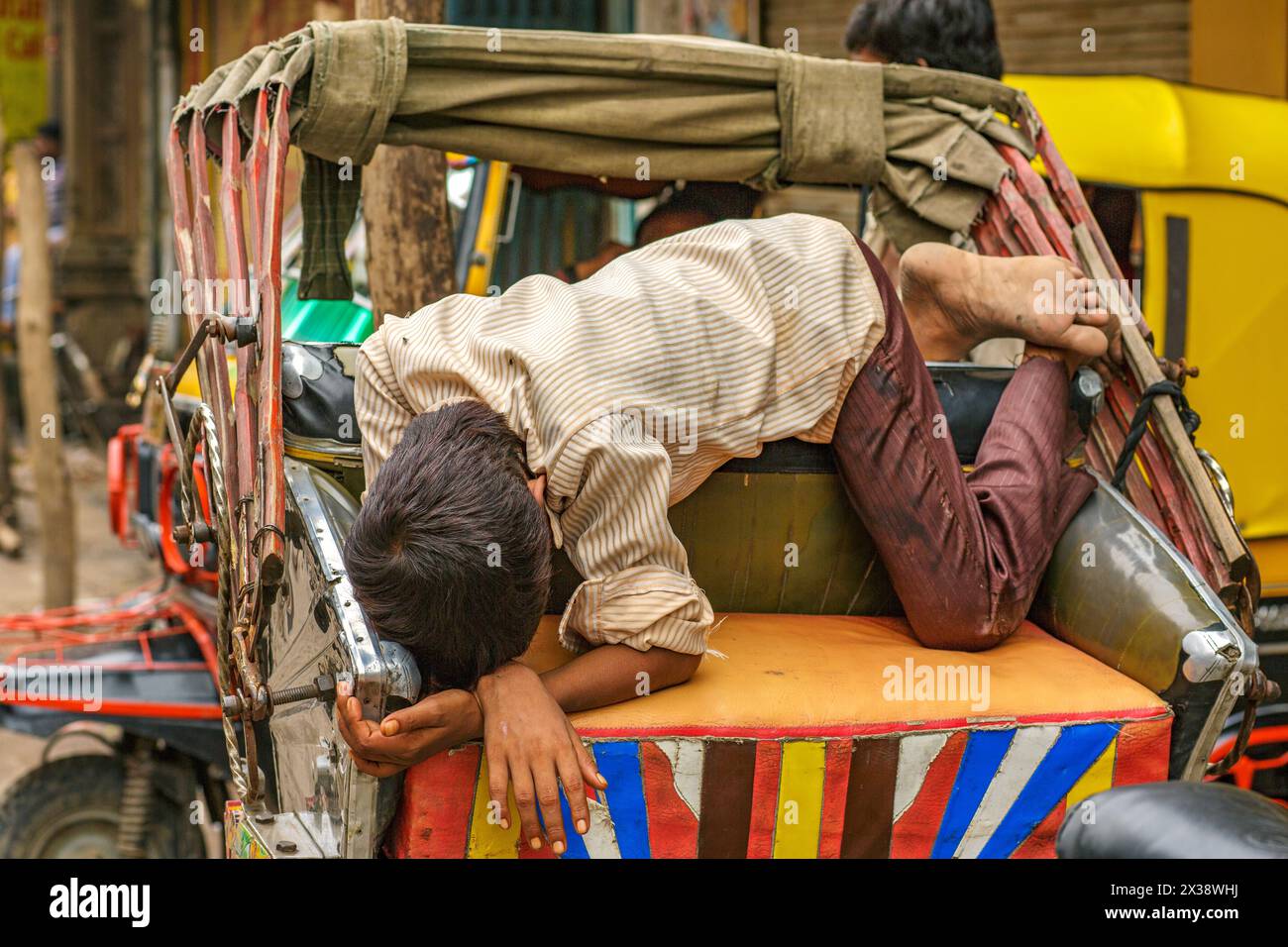 Giovani che dormono sul sedile del passeggero di un risciò cicloturistico a Varanasi, India. Foto Stock