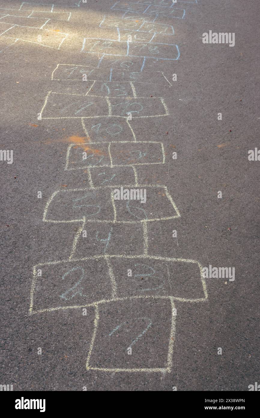 Disegni con gesso su asfalto. Concetto di gioco Hopscotch. Concetto d'infanzia. Numeri dipinti sulla strada. Giochi all'aperto. Attività per bambini. Foto Stock
