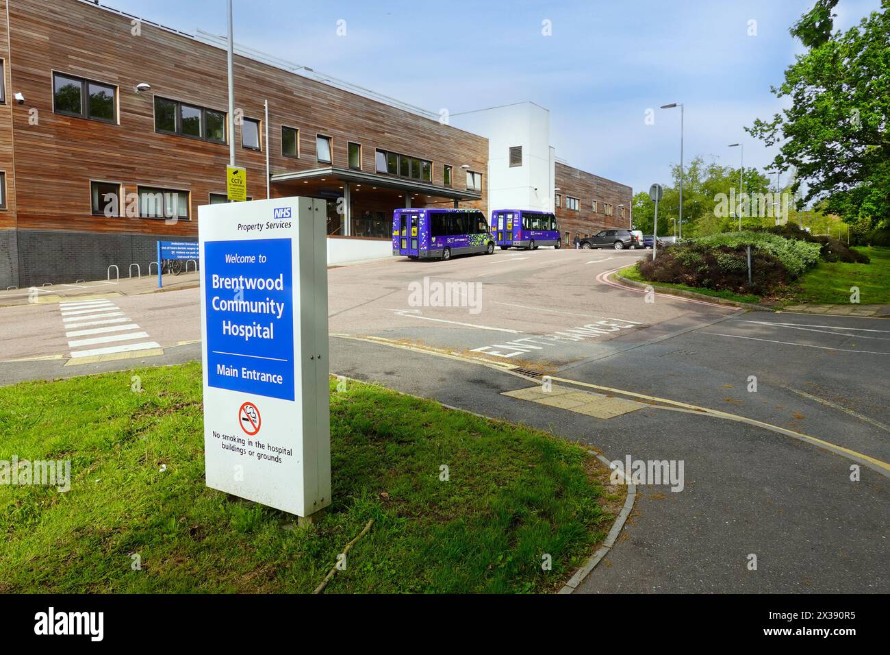 Cartello del NHS Brentwood Community Hospital e edificio per parcheggio auto, uscita di ingresso e ingresso dei pazienti con tettoia alle strutture di accoglienza Essex England UK Foto Stock