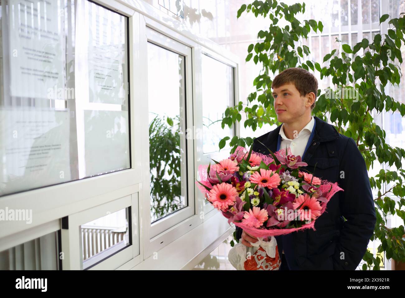 Uomo con grande bouquet di fiori vicino alla finestra di ricevimento in ospedale di maternità Foto Stock