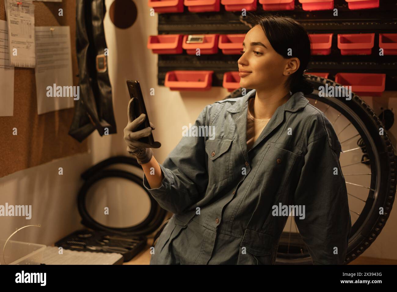 Meccanico di biciclette che lavora in un garage o in un'officina scattando un selfie con il suo smartphone Foto Stock