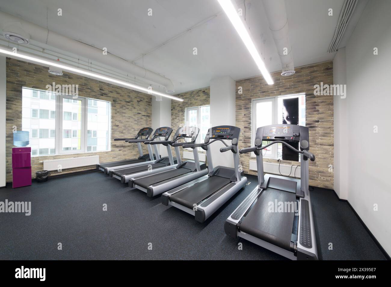Tapis roulant in una moderna sala vuota per il fitness con pareti e finestre in mattoni Foto Stock