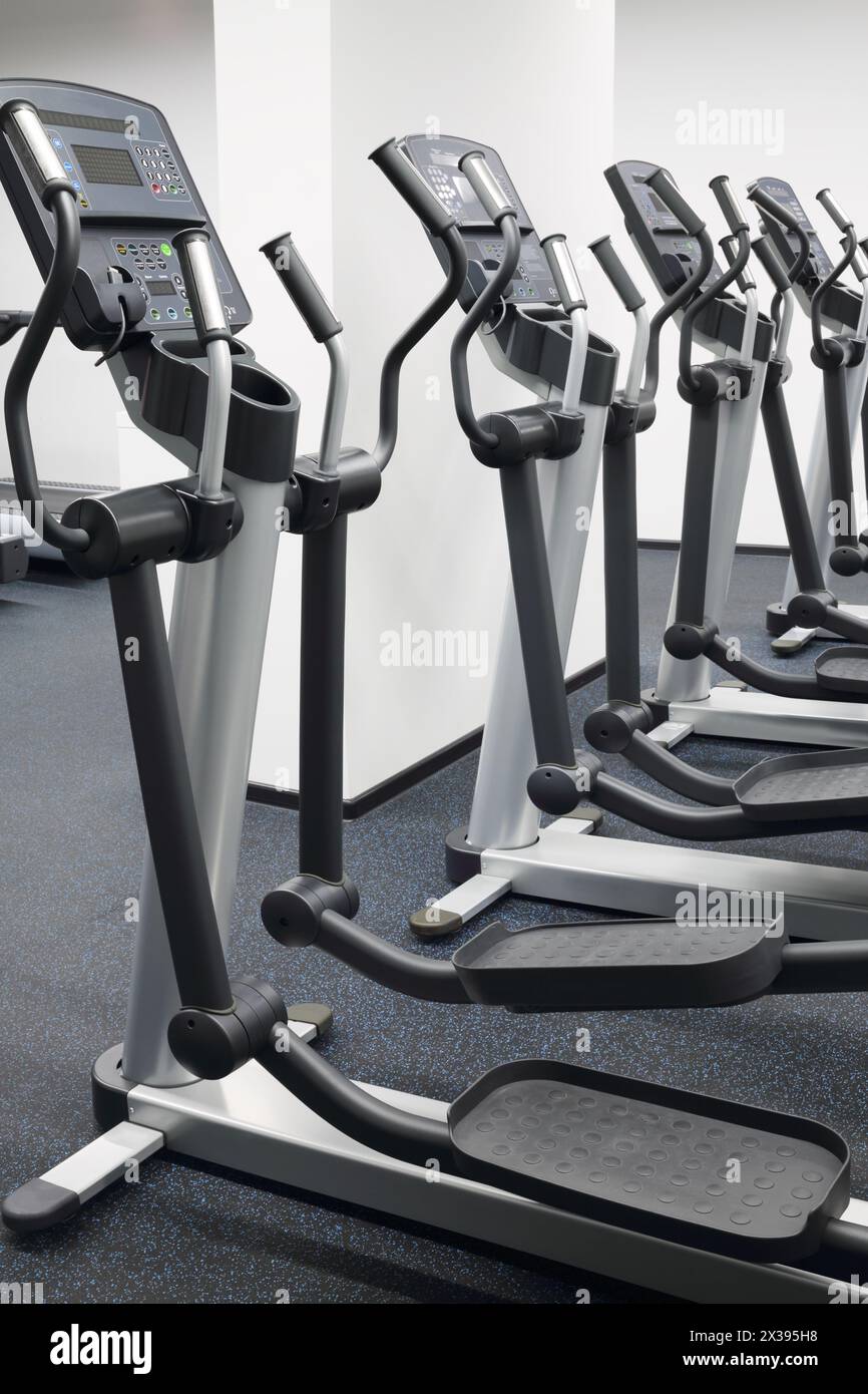 Quattro nuove macchine ellittiche in una sala moderna per il fitness con pareti bianche Foto Stock
