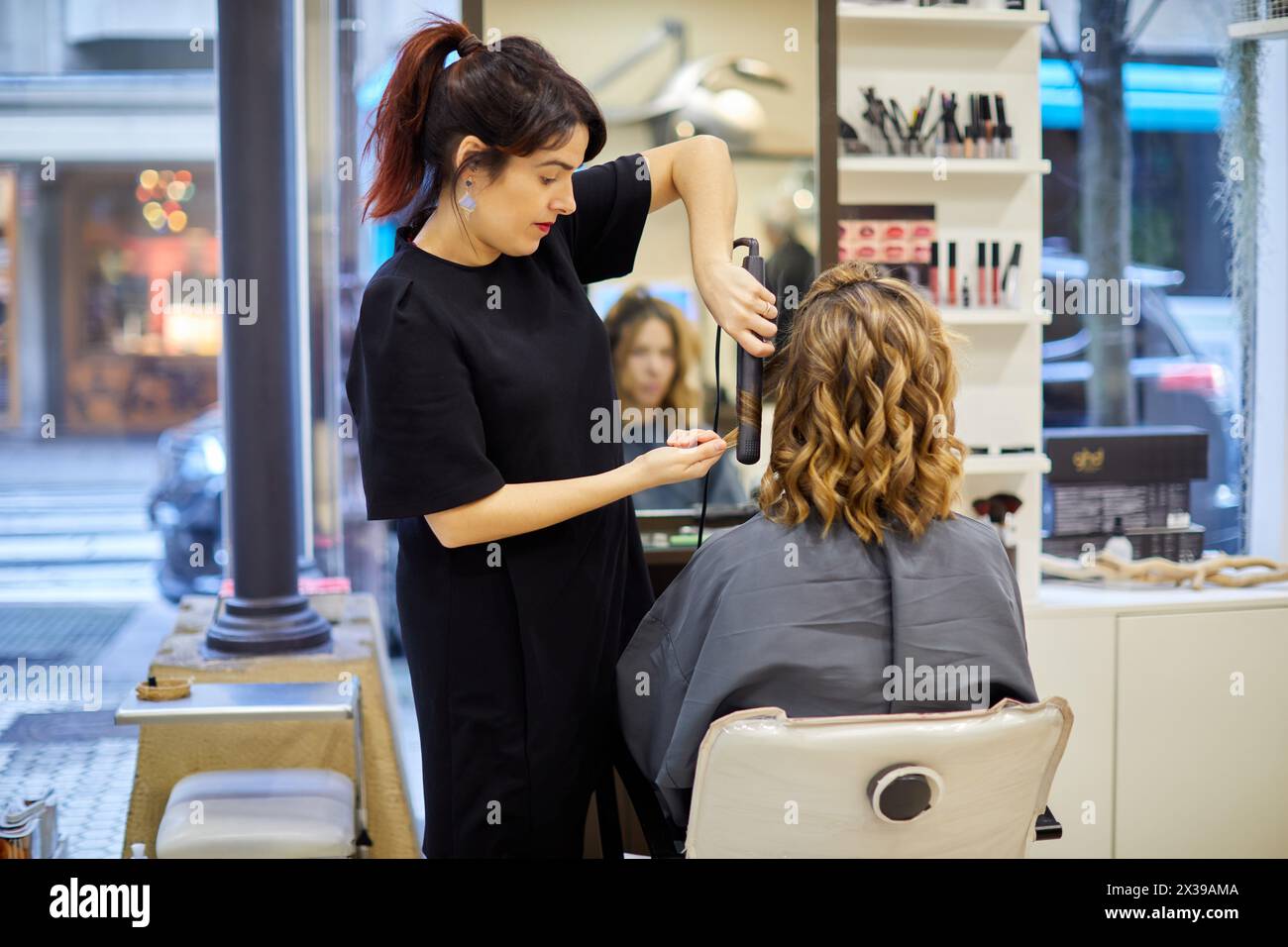 Parrucchiere pettinatrice donna, piastra per capelli, parrucchiere e centro estetico. Foto Stock