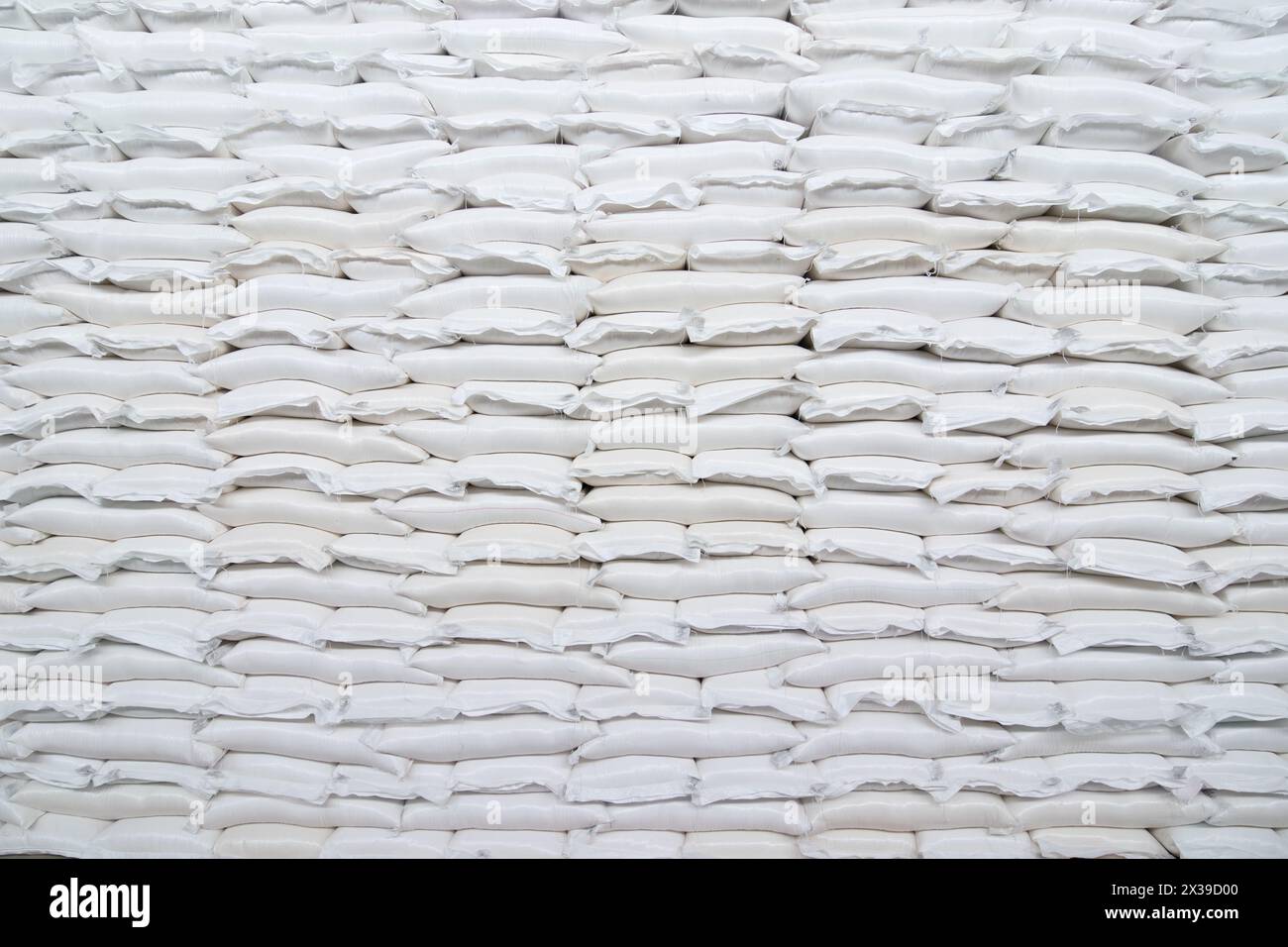 Molte file di sacchi bianchi in plastica con merci si trovano in un grande magazzino Foto Stock