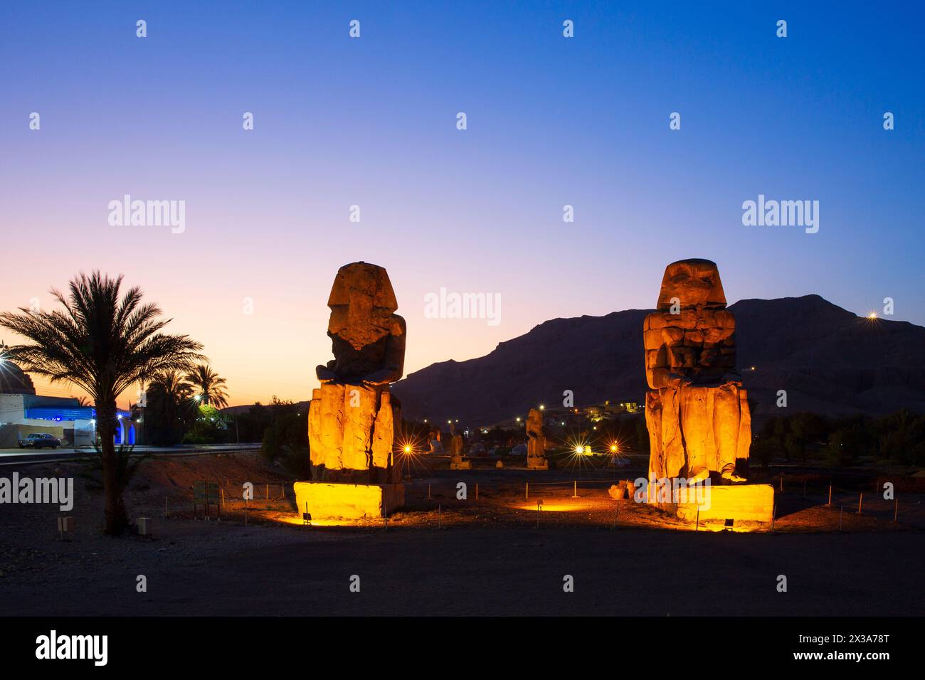 I Colossi di Memnone (colossali statue del faraone Amenofi III) al crepuscolo sulla sponda occidentale di Luxor, in Egitto Foto Stock