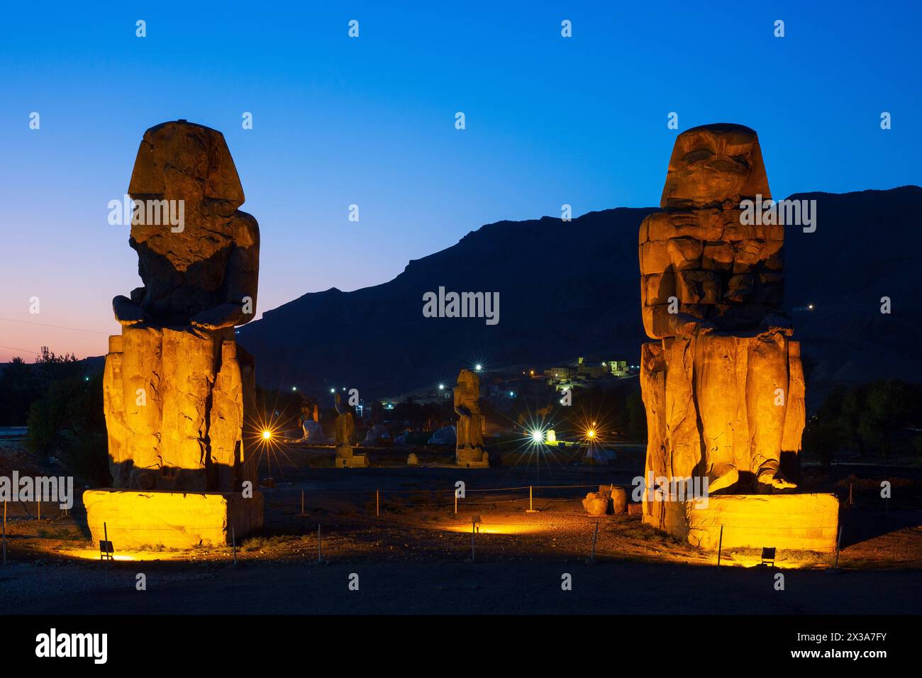 I Colossi di Memnone (colossali statue del faraone Amenofi III) al crepuscolo sulla sponda occidentale di Luxor, in Egitto Foto Stock