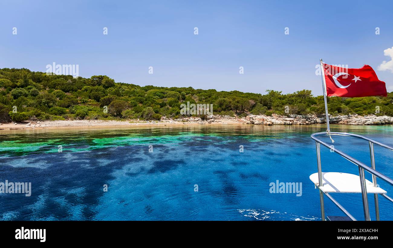 A bordo di una barca per esplorare le splendide coste turchesi di Bodrum. A poppa la bandiera della Turchia Foto Stock