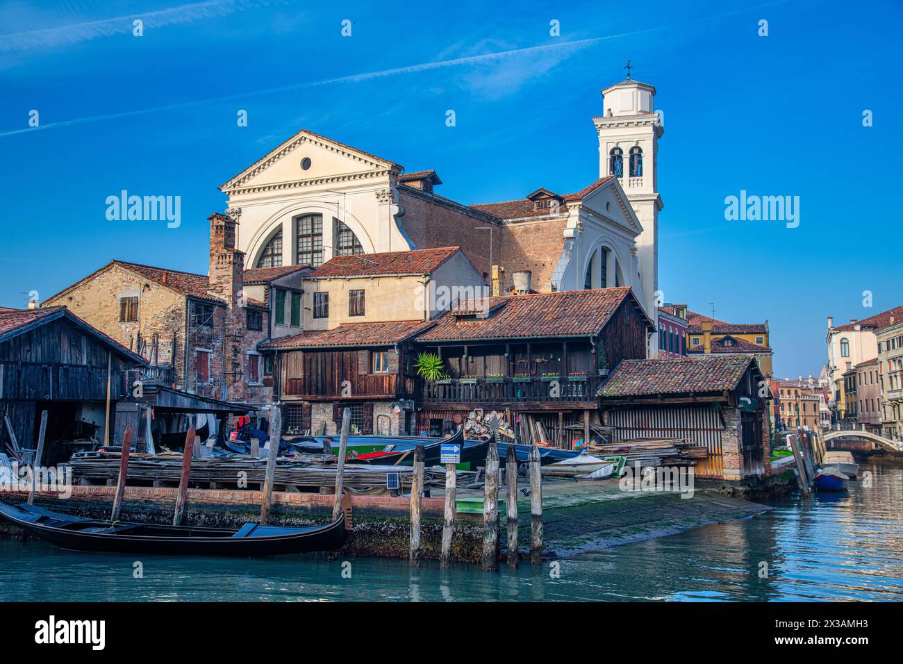 Lo Squero di San Trovaso a Venezia, uno degli ultimi cantieri storici per gondole della città, con la maestosa chiesa di San Trovaso Foto Stock