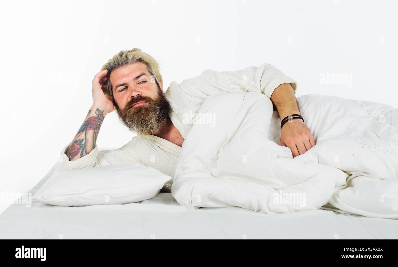 Buon giorno. Bell'uomo barbuto sdraiato a letto, si sveglia la mattina. Uomo attraente in pigiama che si sveglia dopo una buona notte di sonno. Uomo sorridente a letto Foto Stock