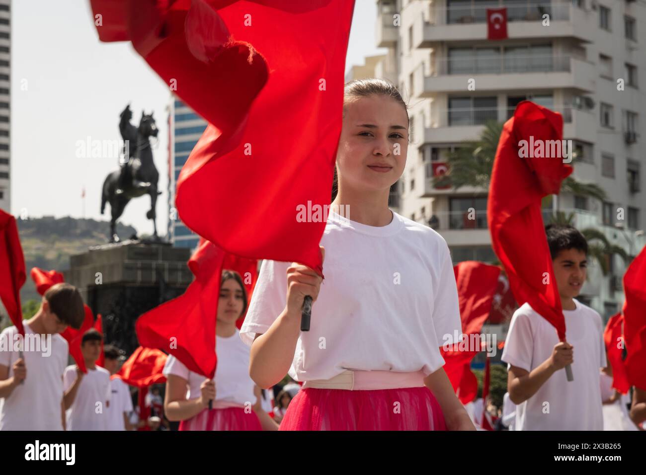 Izmir, Turchia - 23 aprile 2024: Una vista ravvicinata di un giovane studente che detiene una bandiera turca, con gli altri partecipanti che sventolano bandiere sullo sfondo, du Foto Stock