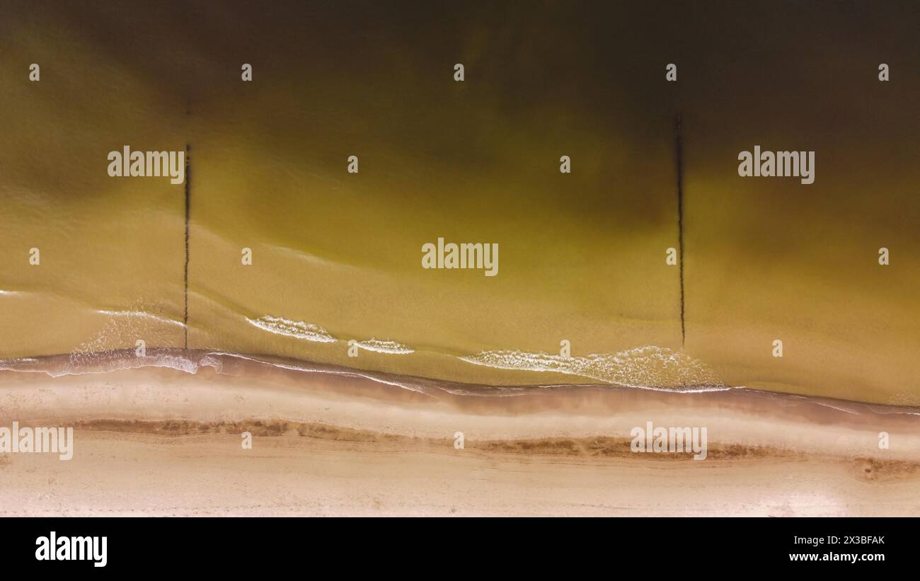 Ripresa aerea di una spiaggia tranquilla con onde dolci e lunghe ombre durante l'ora d'oro, vista aerea della spiaggia Foto Stock