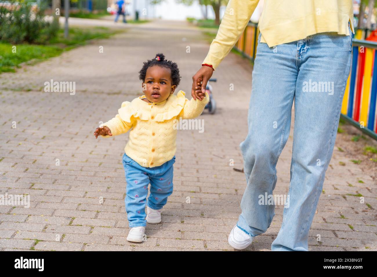 Irriconoscibile madre africana e bambina che camminano tenendosi per mano in strada Foto Stock