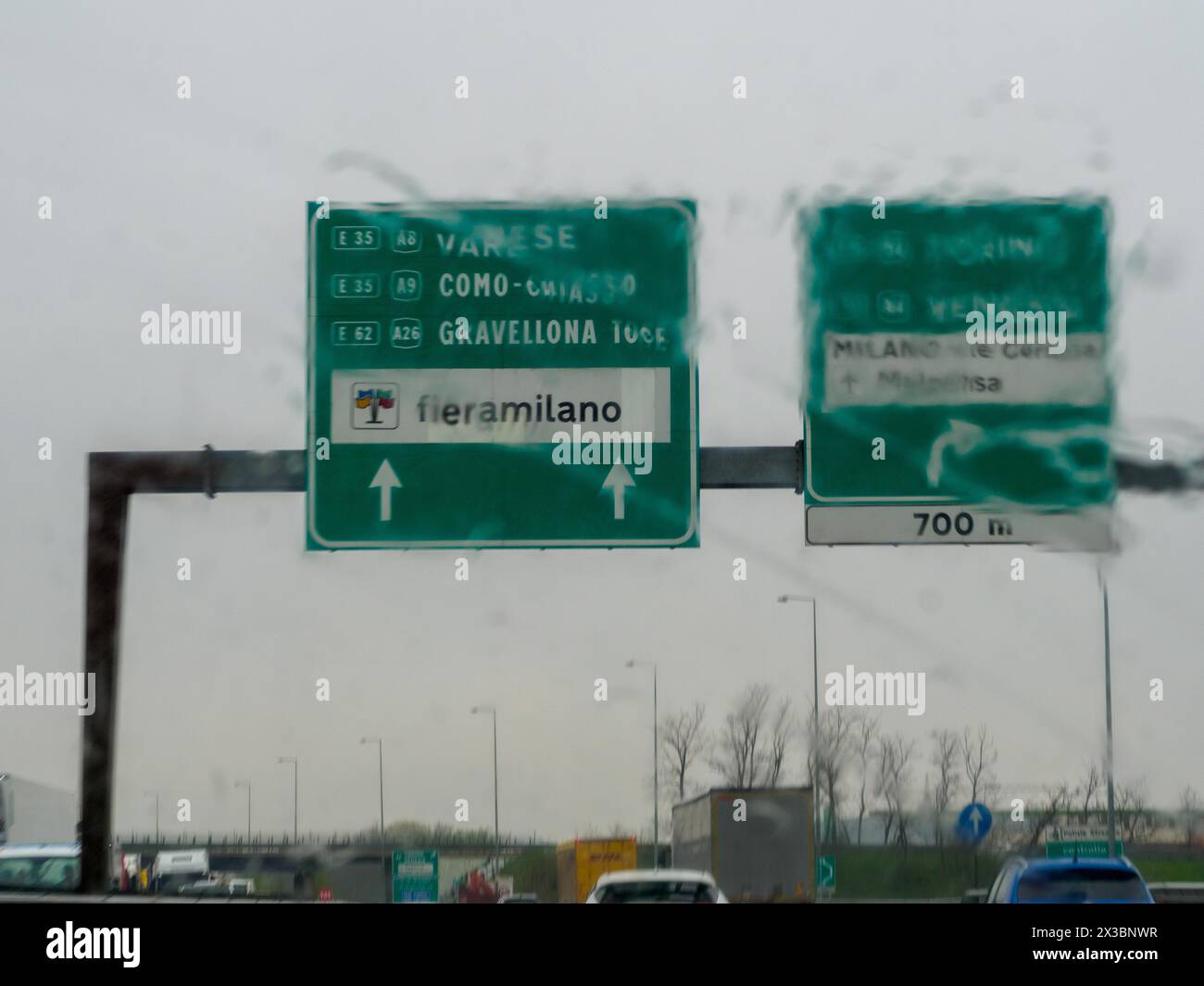Vista sfocata dei segnali stradali di destinazione in un giorno di pioggia attraverso il parabrezza di un veicolo, A1 A8 vicino a Milano, Italia, Europa Foto Stock