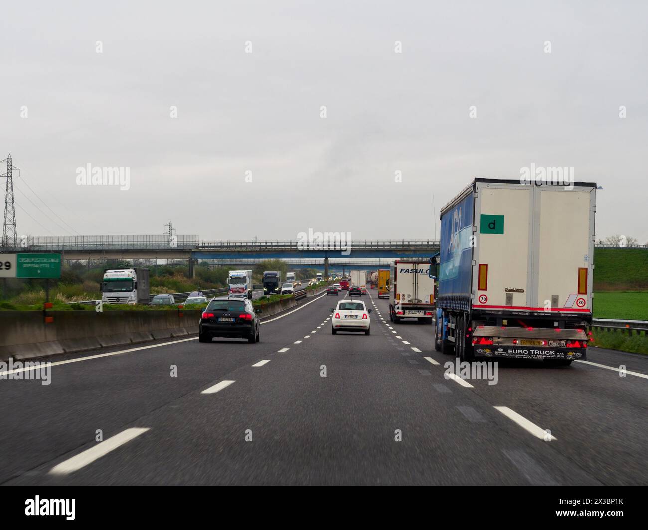 Vista di un'autostrada con più corsie di traffico e segnali stradali in una giornata nuvolosa, autostrada A1 A8 vicino a Milano, Italia, Europa Foto Stock