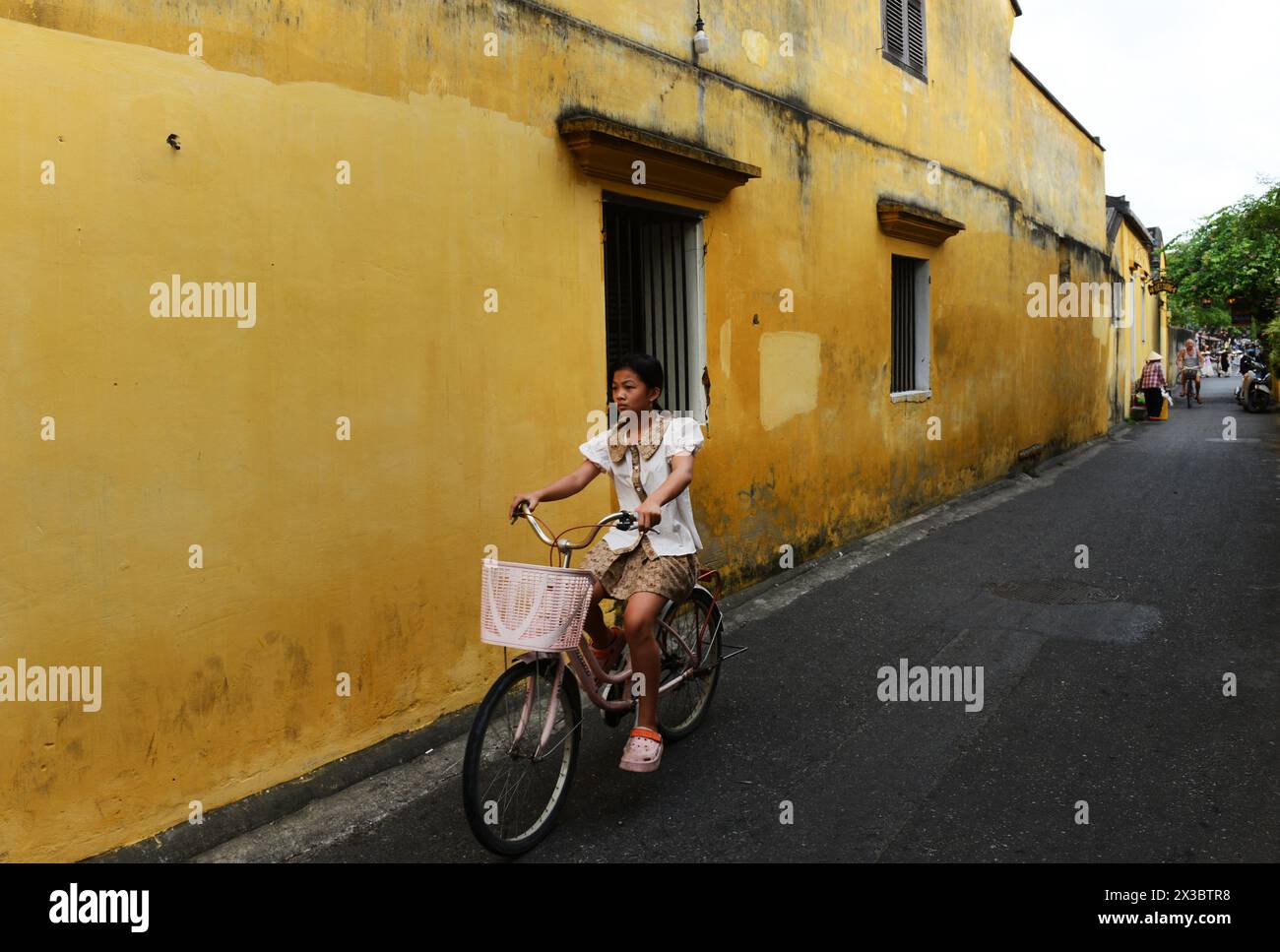 Una donna vietnamita in bicicletta nella città vecchia di Hoi An, Vietnam. Foto Stock
