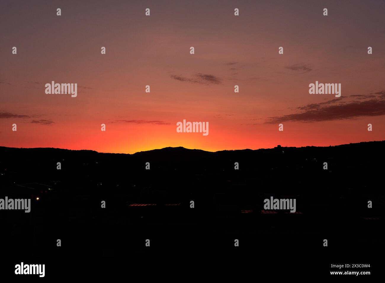 Il cielo arancione rossastro all'alba con le sagome delle montagne crea la sensazione di calma, meditazione e bellezza della natura. Foto Stock