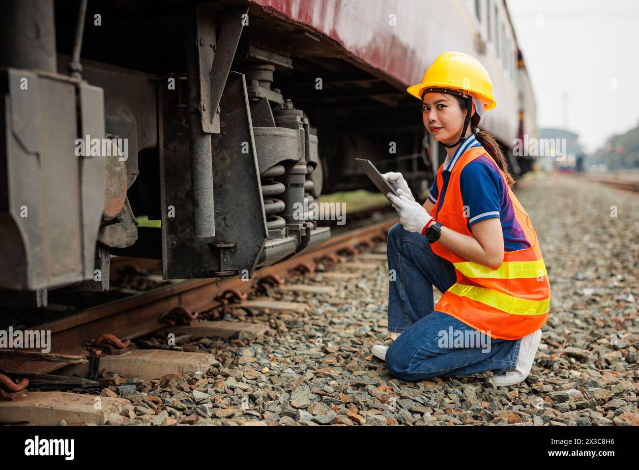 Lavoratore donna ingegnere locomotiva. Giovani adolescenti asiatici lavoro controllare servizio di manutenzione treno utilizzando software per tablet computer. Foto Stock