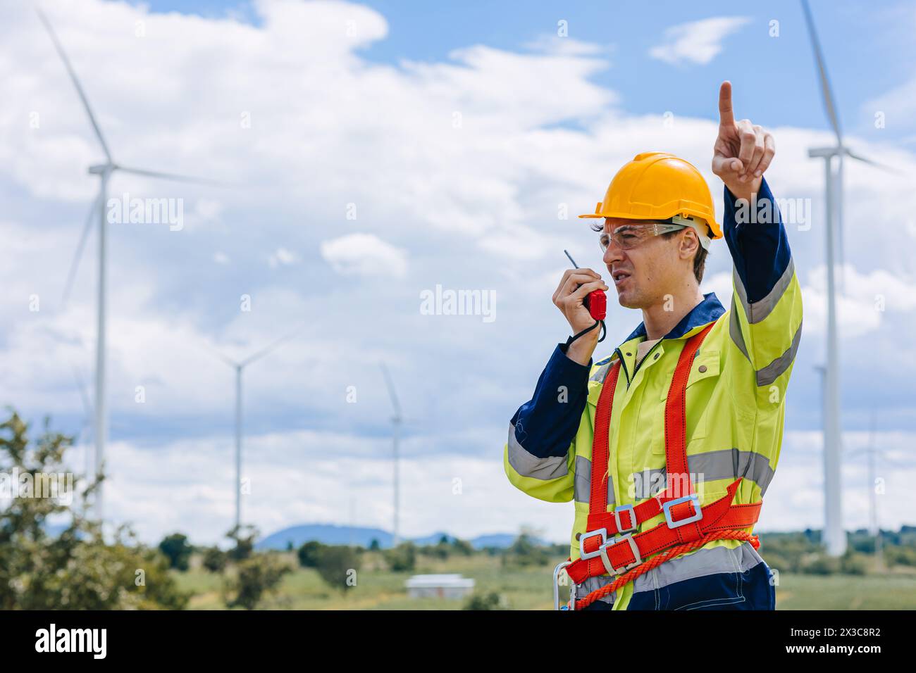 il controllo maschio dell'ingegnere opera sul campo manutenzione esterna del servizio generatore eolico. mano del lavoratore che punta la posizione al gesto dell'ordine Foto Stock