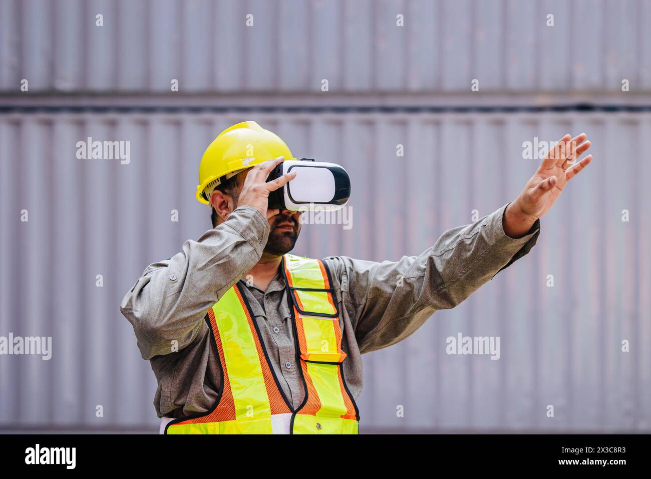 I lavoratori che utilizzano dispositivi con cuffie e auricolari VR Vision Pro Technology lavorano presso Container Yard Construction Site innovazione nel settore della logistica Foto Stock