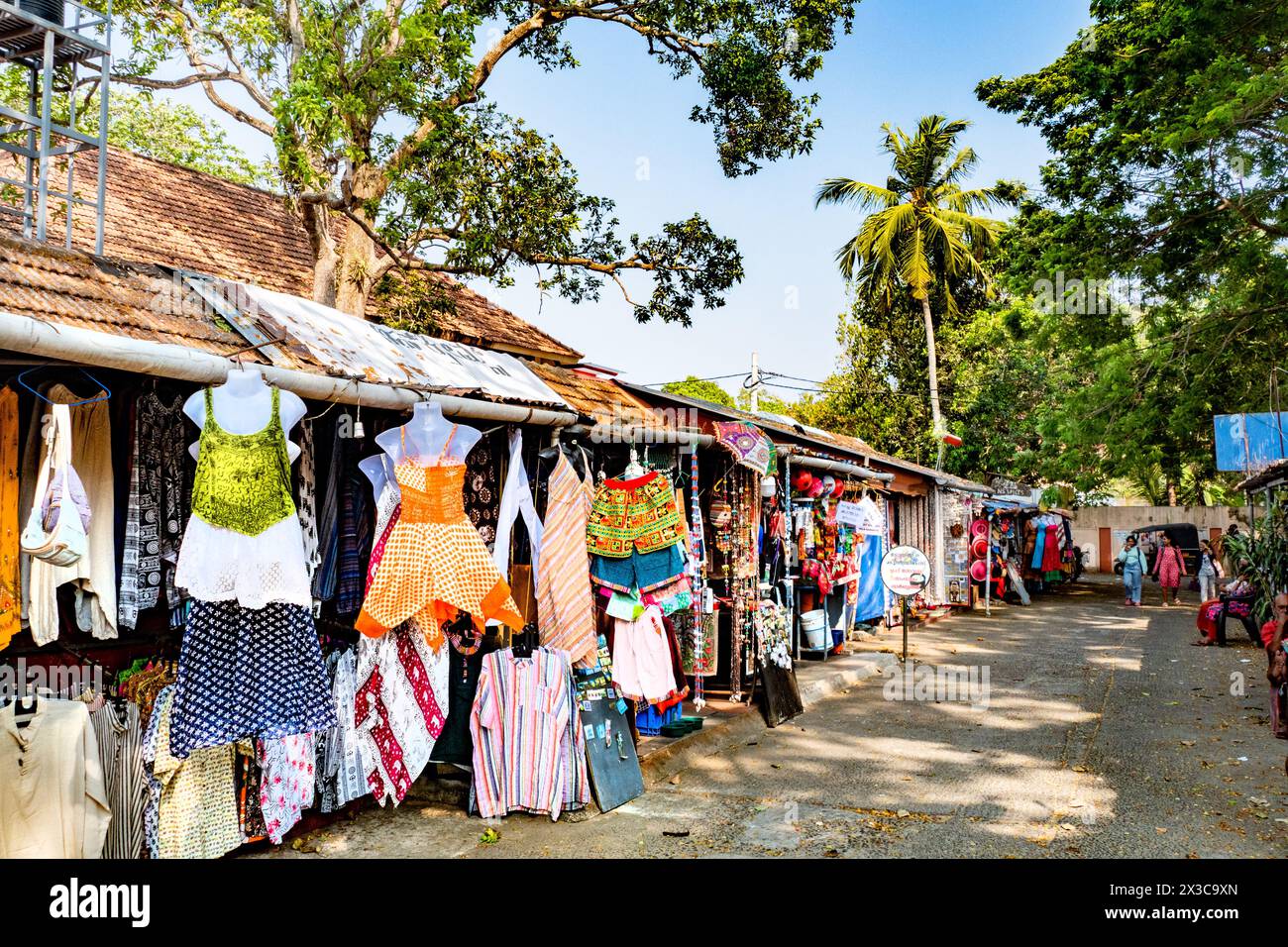 Cochin, India - 22 marzo 2024: Le persone vendono vestiti colorati ai turisti circondati da grandi palme. Foto Stock