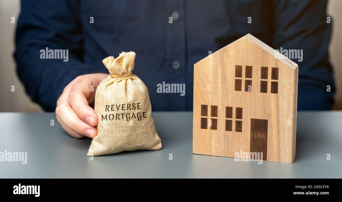Concetto di mutuo inverso. Consentire ai proprietari di case di prendere in prestito denaro utilizzando la loro casa come garanzia per il prestito. Borsa dei soldi nelle mani di un uomo d'affari Foto Stock