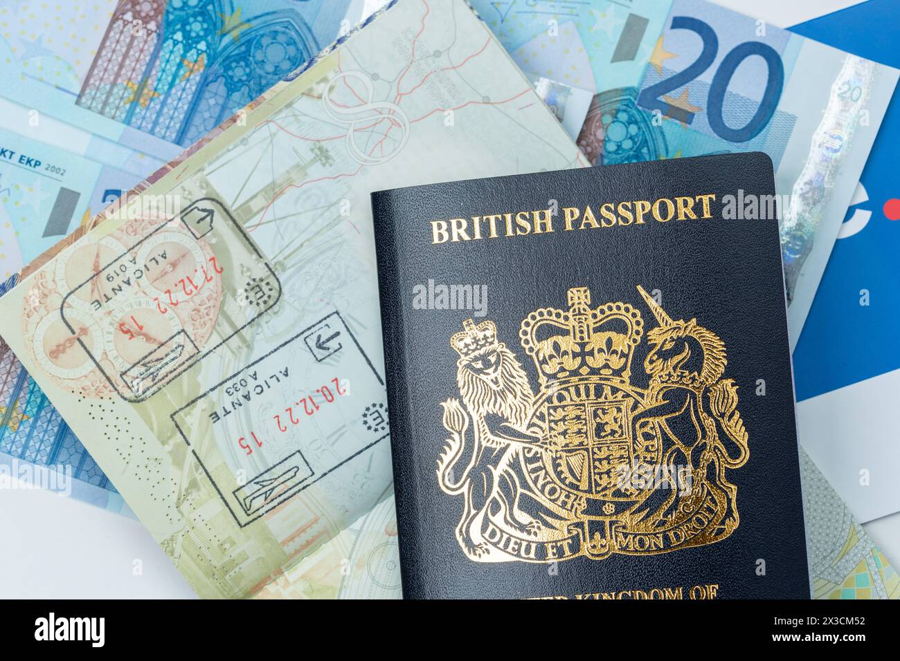 Chiudere un nuovo passaporto britannico blu con banconote in euro sullo sfondo Foto Stock
