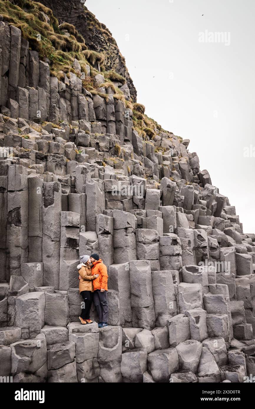 Coppia che si baciano tra torreggianti colonne di basalto in Islanda Foto Stock