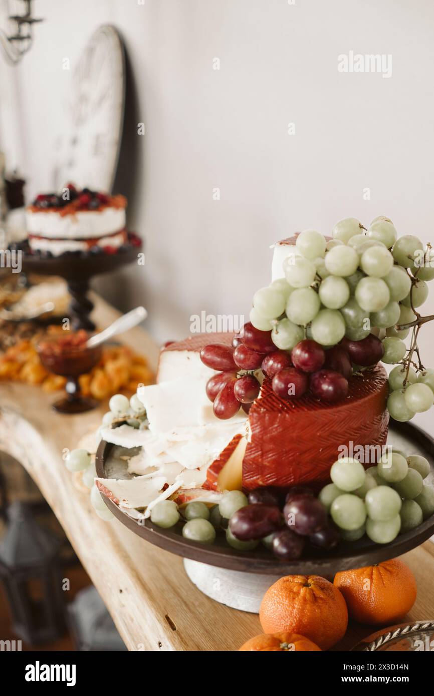 Piatto di formaggi artigianali con uve e arance vivaci. Foto Stock