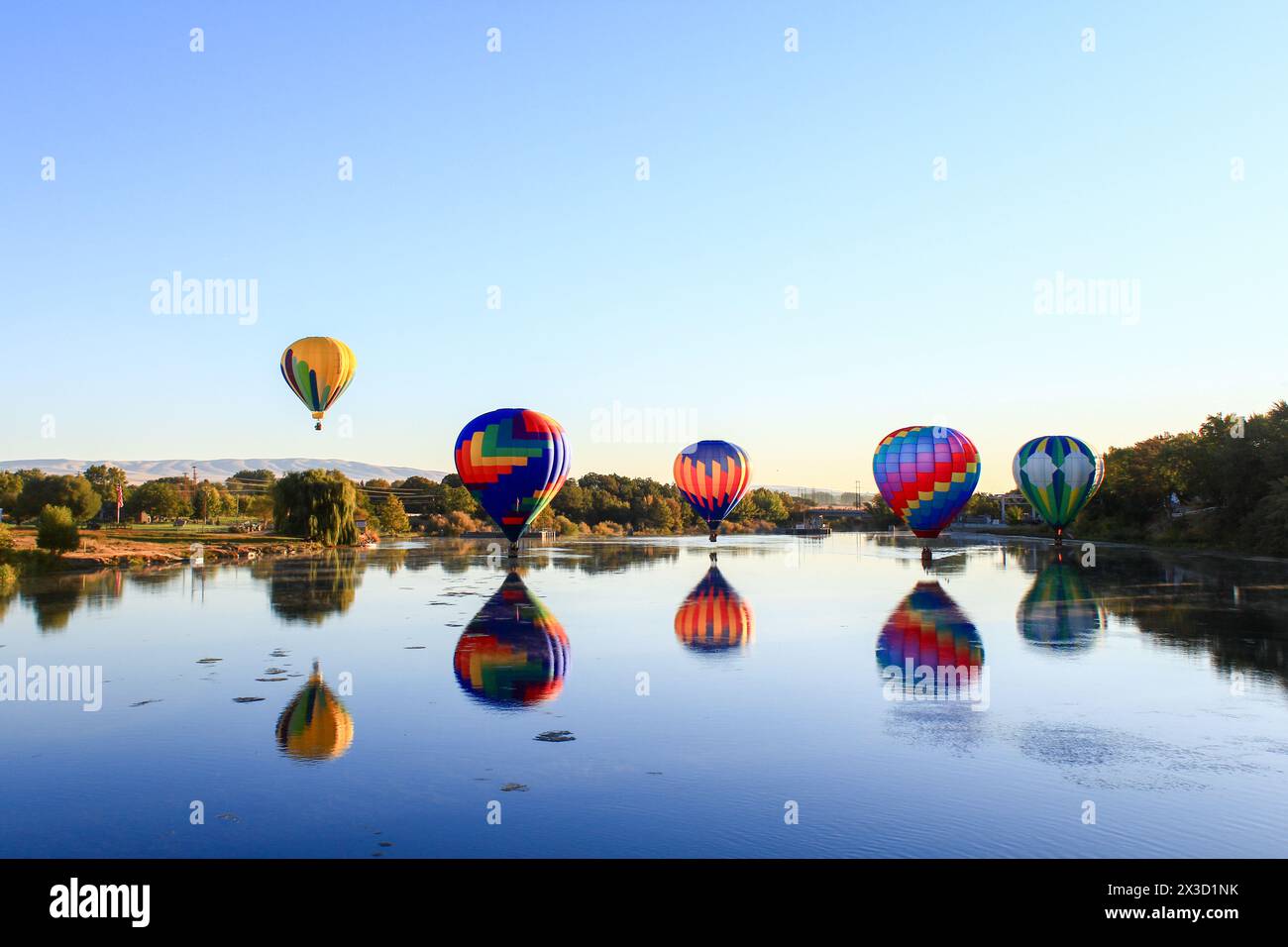 Salita all'alba di palloncini vibranti sull'acqua Foto Stock