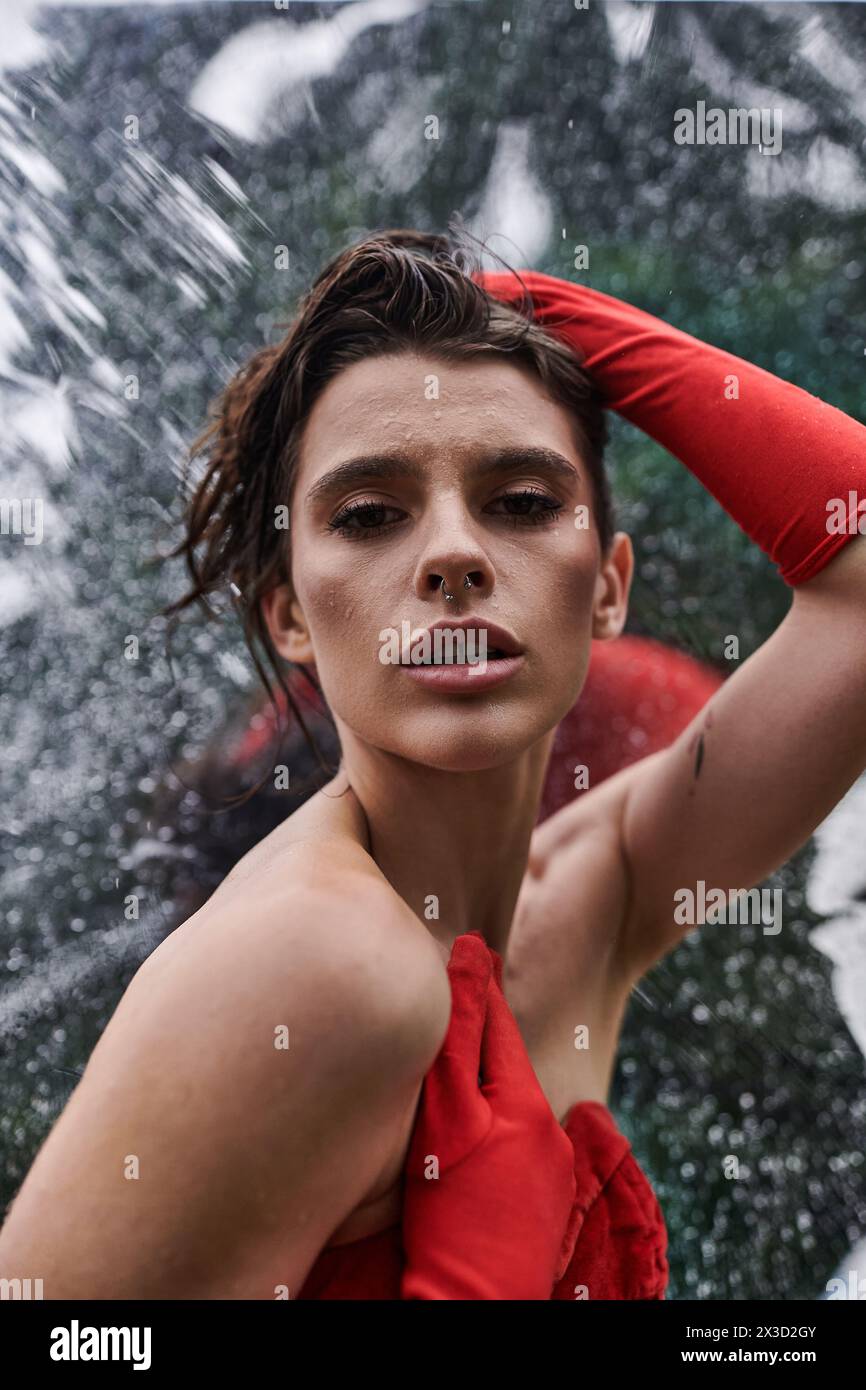 Una giovane donna con un abito rosso e guanti lunghi godendosi la brezza estiva Foto Stock