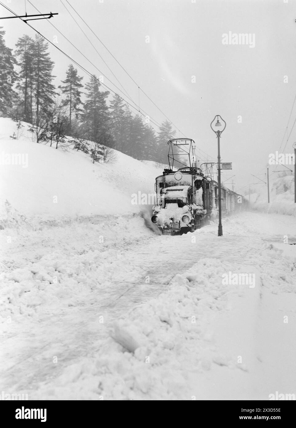 Effettivo 05- 1951: Norvegia meridionale coperta di neve. Lungo le strade, i bordi dell'aratro alti quattro cinque metri, la neve è così alta che si può facilmente uscire dal secondo piano e le persone devono costantemente salire sui tetti per liberare la neve da lì. Due volte il Sørlandsbanen è stato bloccato dalla neve quest'inverno. Il treno di Oslo passa da Vegårshei mercoledì 21 febbraio. Fu il primo treno sulla rotta in 3½ giorni. 0g prima che arrivasse, c'era un sacco di sudore sulla linea ferroviaria. Foto: Arne Kjus / Aktuell / NTB ***la foto non è stata elaborata*** il testo dell'immagine viene tradotto automaticamente Foto Stock