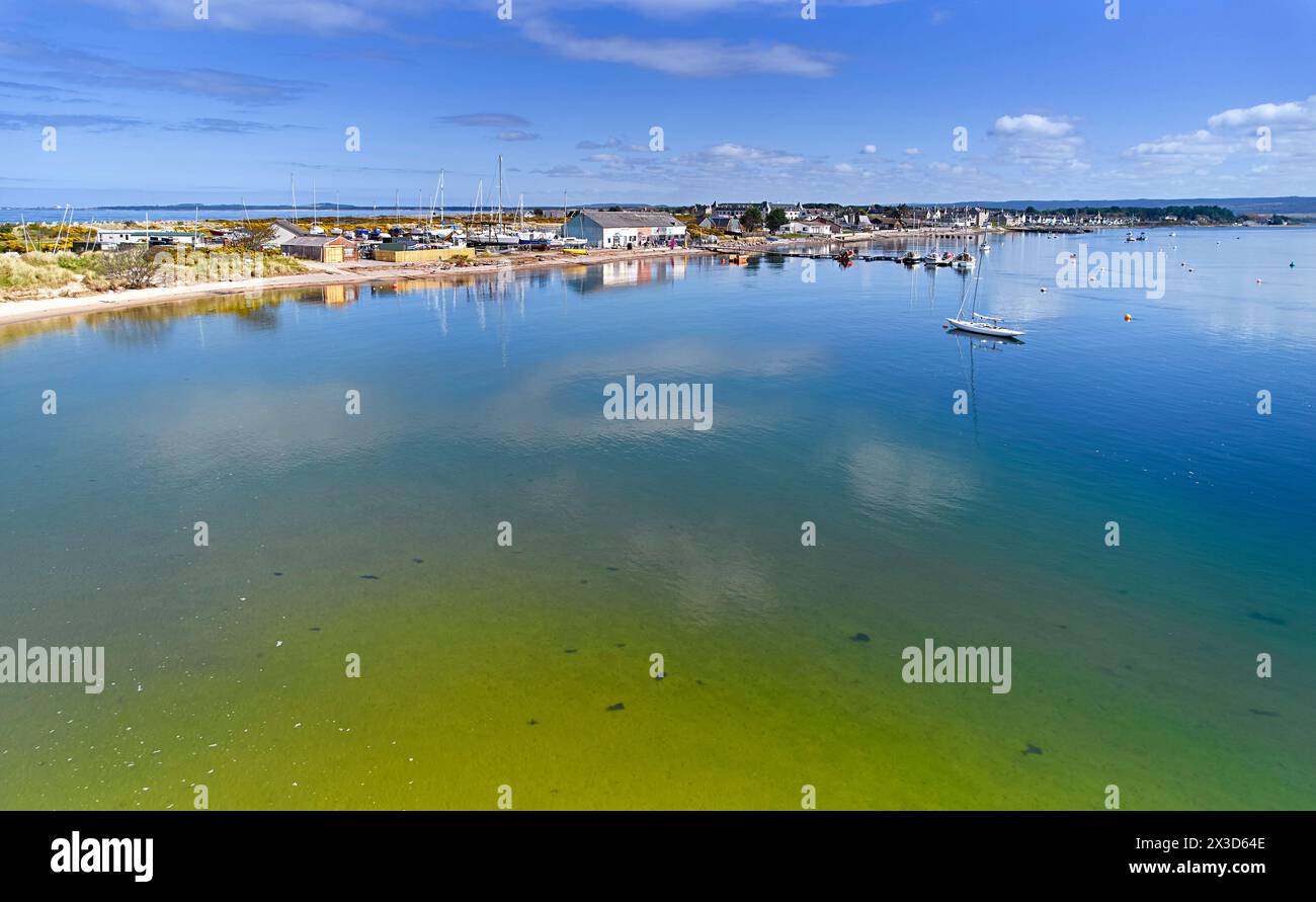 Findhorn Moray Coast Scozia cielo blu sopra le case del villaggio e mare calmo della baia durante l'alta marea Foto Stock