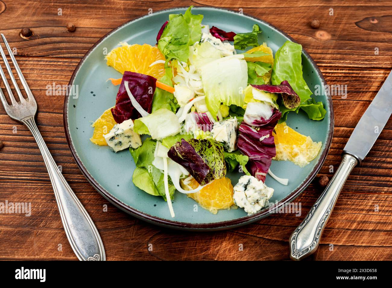 Insalata sana e succosa con verdure, arancia e formaggio su sfondo rustico. Foto Stock