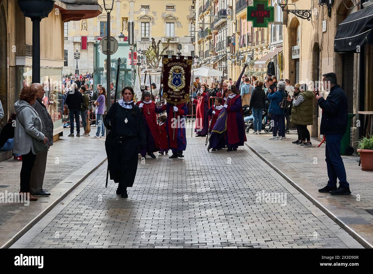 Tarragona, Spagna - 26 aprile 2024: Una processione della settimana Santa si svolge in una strada di Tarragona, con persone vestite con abiti tradizionali e spectato Foto Stock