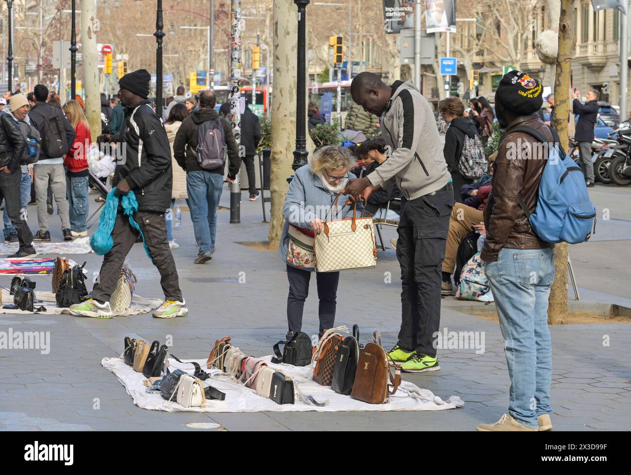 Migranten verkaufen Taschen, gefälschte Markenware, Passeig de Gracia, Barcellona, Katalonien, spagnolo Foto Stock