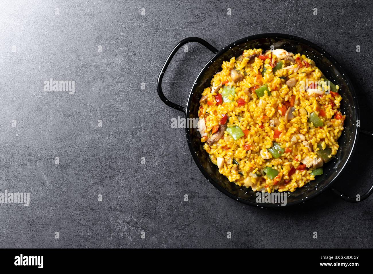 Riso giallo con pollo e verdure su sfondo di ardesia nera Foto Stock