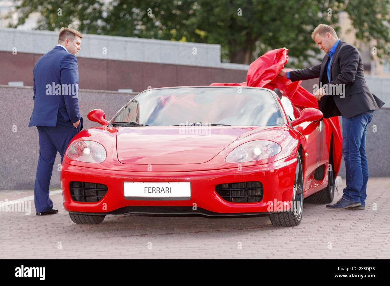 MOSCA, RUSSIA - 22 giugno 2016: Due uomini d'affari di successo (con versioni di modelli) che si accingeranno a guidare una supercar rossa di lusso Ferrari Foto Stock