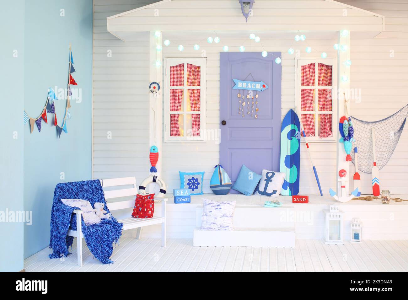 L'interno della facciata bianca della casa con un portico e una porta lilla con una spiaggia a puntatore in stile marino Foto Stock