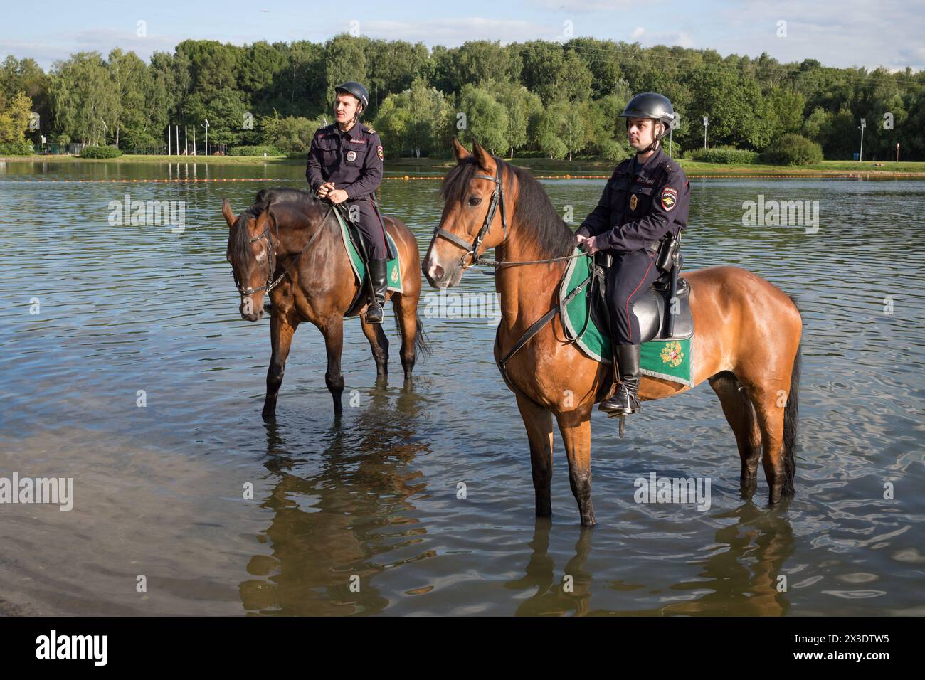 Due poliziotti a cavallo sono in piedi nello stagno Putyaevsky al parco Sokolniki. Foto Stock