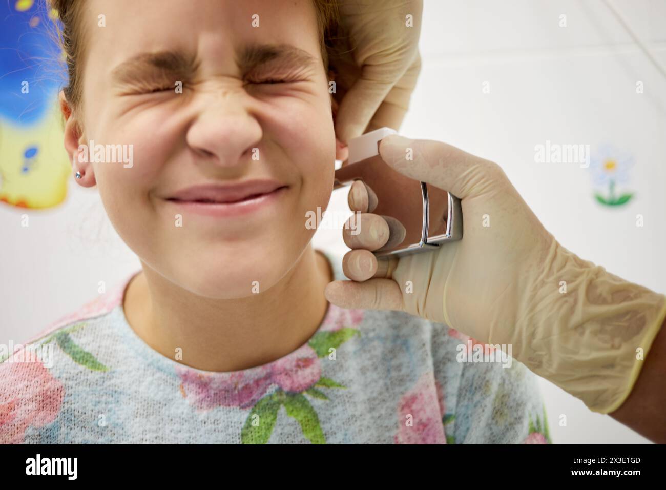 Mani del medico che fanno perforare l'orecchio a una ragazza adolescente. Foto Stock