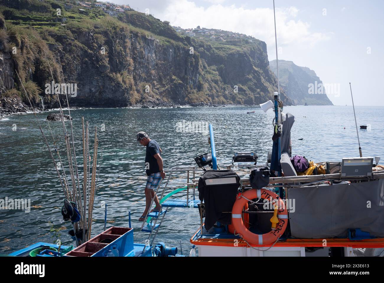 Un pescatore portoghese scende a bordo della sua barca ormeggiata in una banchina della costa meridionale, il 18 aprile 2024, a Ribeira Brava, Madeira, Portogallo. Foto Stock