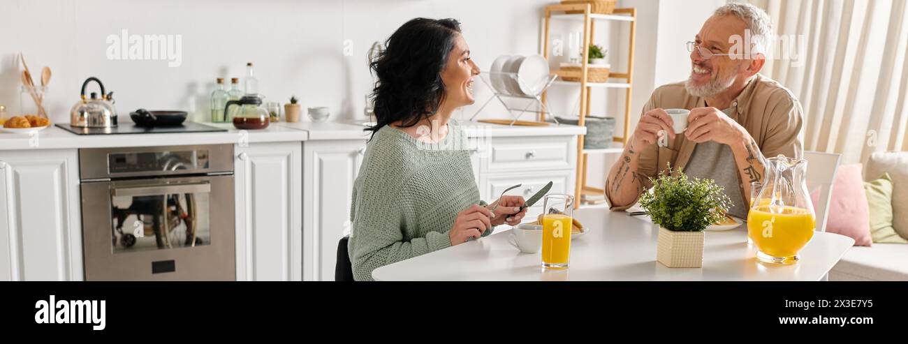 Una donna disabile in sedia a rotelle e il suo devoto marito siedono a un tavolo della cucina, condividendo un momento speciale insieme. Foto Stock