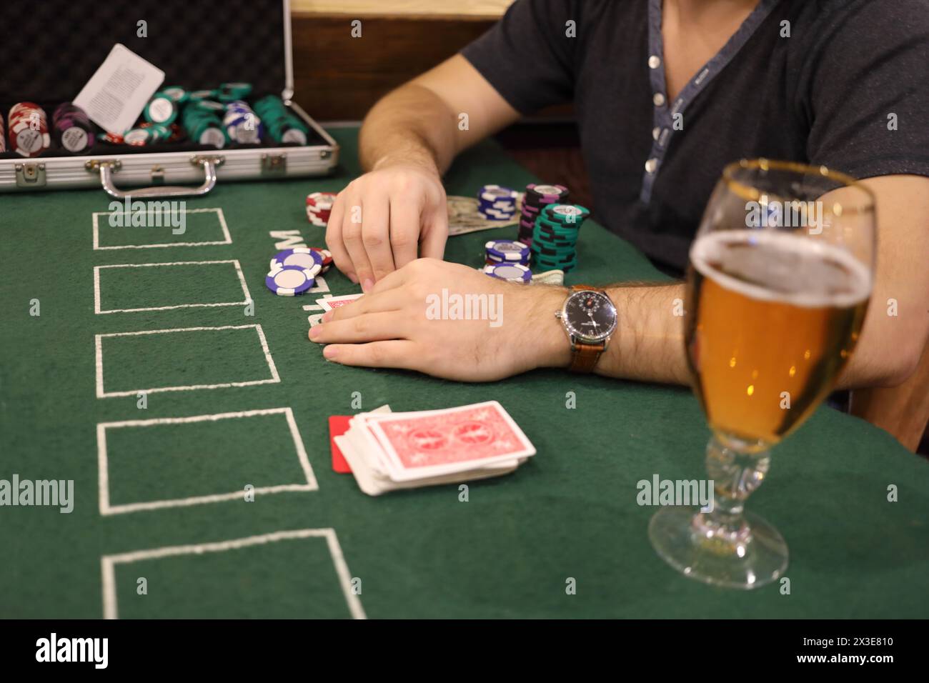 Mani maschili, patatine da casinò in caso, birra di cartone sul green table durante la partita Foto Stock