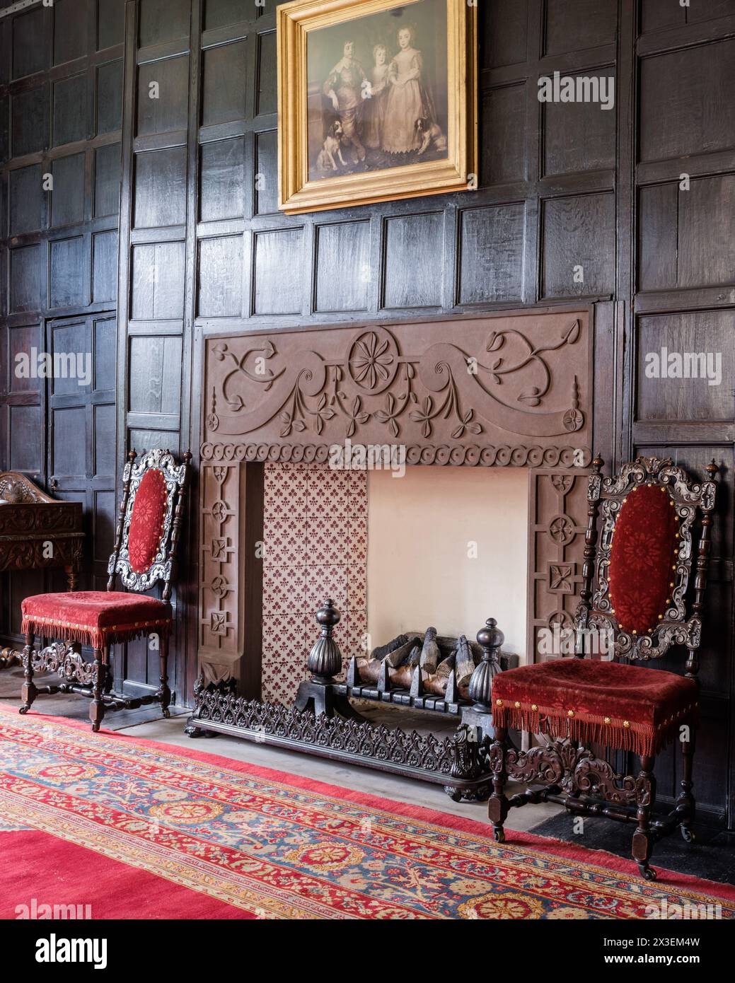 Sedie in velluto rosso al caminetto di Speke Hall, residenza Tudor di livello i, Liverpool, Inghilterra, Regno Unito. Foto Stock