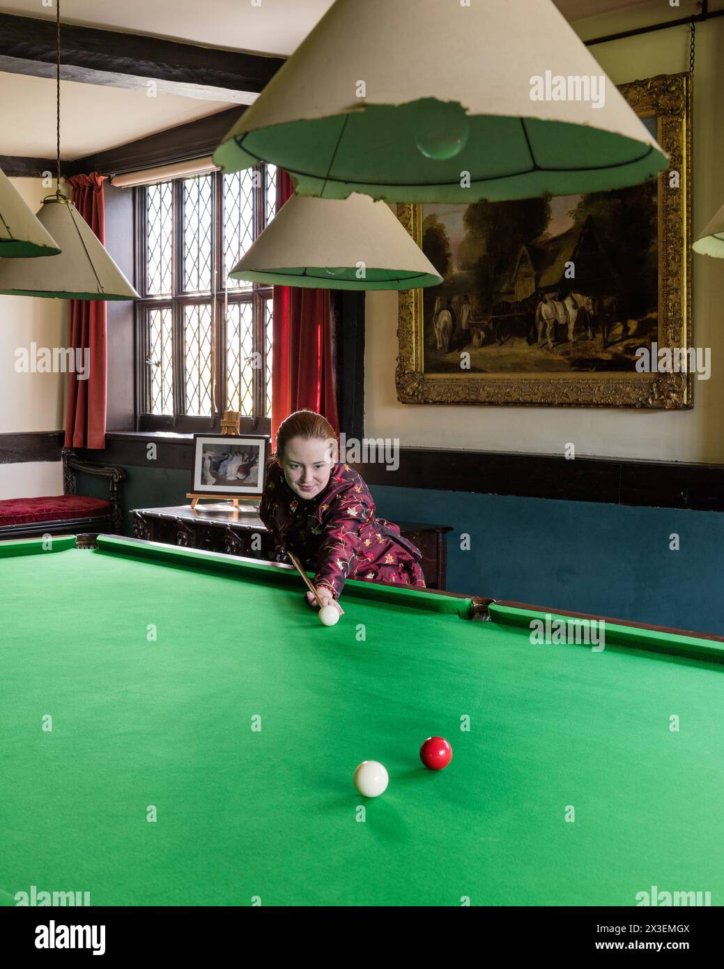 Donna che gioca a biliardo nella Speke Hall, residenza Tudor del National Trust di grado i, Liverpool, Inghilterra, Regno Unito. Foto Stock