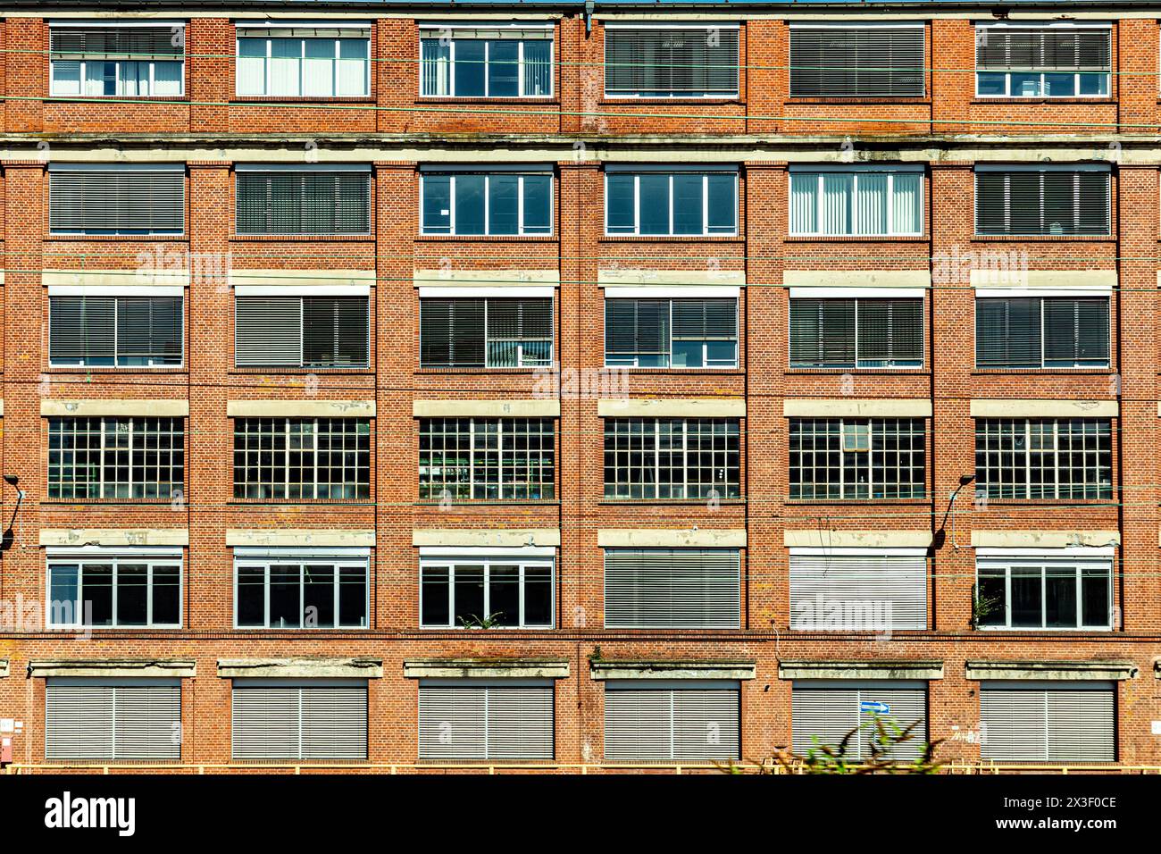 facciata di un vecchio edificio in mattoni con diverse finestre e persiane, chiuse, opposte Foto Stock