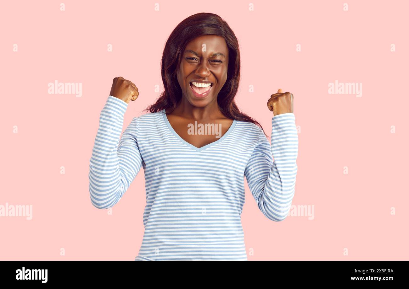 African American Young Woman Exclaim Sì su sfondo rosa Foto Stock